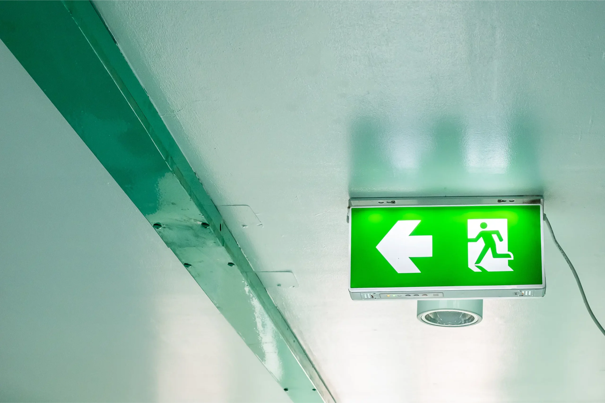 Illuminated emergency exit sign above a doorway on an interior escape route